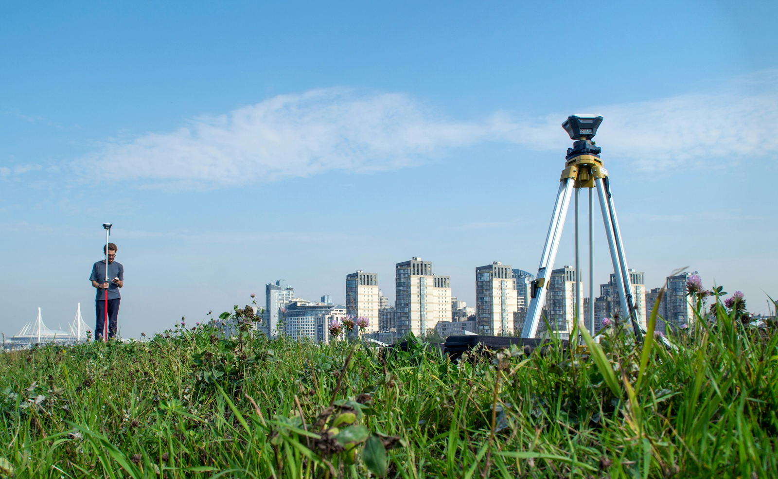 Land surveyor and surveying equipment in the field outside of a city